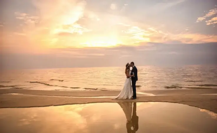 Bride and groom on the beach during sunset to illustrate love. By Анна Ковальчук/stock.adobe.com