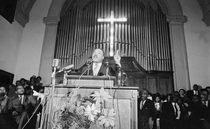 Dr. Martin Luther King Jr., center, speaks to a wildly cheering crowd of African American supporters, Jan. 2, 1965, Selma, Ala. King was calling for a new African American voter registration drive throughout Alabama and promising to "march on the ballot boxes" unless African American are given the right to vote. (AP Photo/Horace Cort)