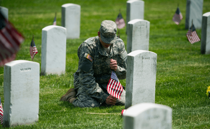 Army Pvt. II Dylan Conway, 19, of Mason, Mich., of the 3rd U.S. Infantry Regiment, also known as The Old Guard, places flags at grave sites at Arlington National Cemetery in Arlington, Va., Thursday, May 22, 2014, as part of the annual "Flags-In" ceremony in preparation for Memorial Day. (AP Photo/Cliff Owen)