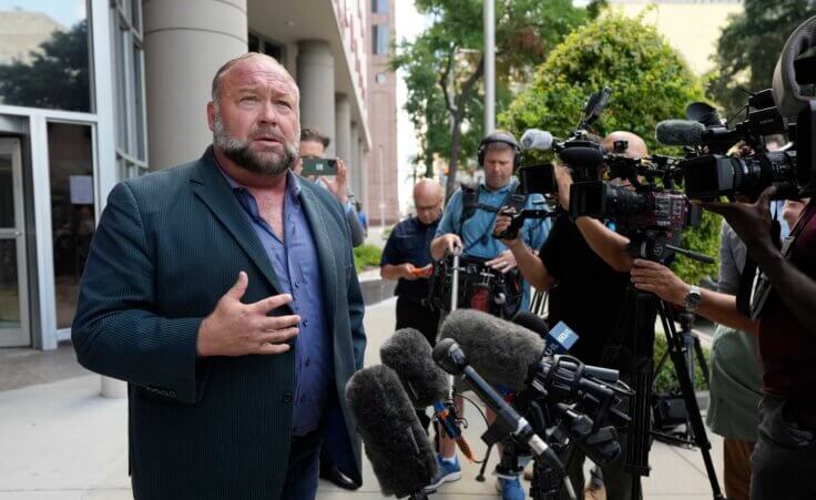 Right-wing conspiracy theorist Alex Jones speaks to the media as he arrives at the federal courthouse for a hearing in front of a bankruptcy judge Friday, June 14, 2024, in Houston. The judge is expected to rule on whether to liquidate Jones' assets to help pay the $1.5 billion he owes for his false claims that the Sandy Hook Elementary School shooting was a hoax. (AP Photo/David J. Phillip)