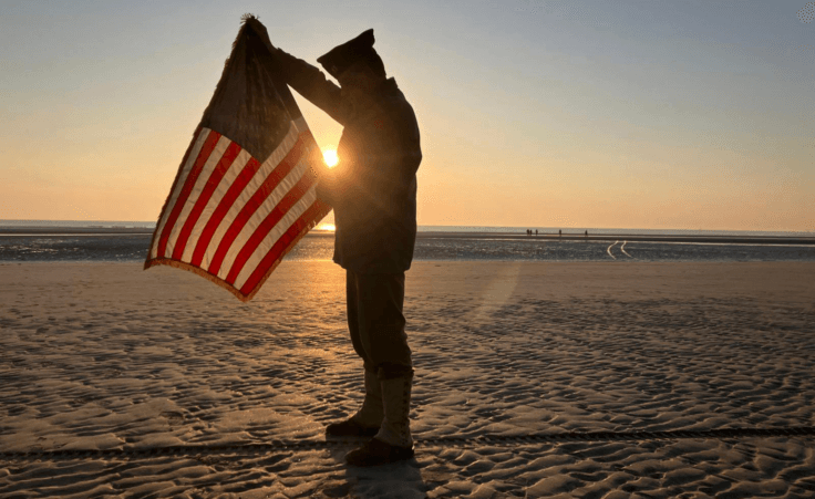 Christophe Receveur, of France, unfurls an American flag he bought six month ago in Gettysburg, Penn., to mark D-Day, Thursday, June 6, 2024 on Utah Beach, Normandy. As the sun sets on the D-Day generation, it's rising again over Normandy beaches where soldiers fought and died exactly 80 years ago, kicking off intense anniversary commemorations Thursday against the backdrop of renewed war in Europe, in Ukraine. (AP Photo/John Leicester)
