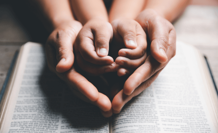 Parent holding child's hands over an open bible. By doidam10/stock.adobe.com. Pastor's six-year-old dies by tragedy on vacation. Lucy Morgan.