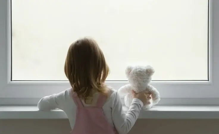 Little girl holding white teddy bear and standing alone at window. By fotoduets/stock.adobe.com Mass shooting Arkansas Callie Weems