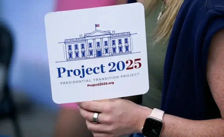 Kristen Eichamer holds a Project 2025 fan in the group's tent at the Iowa State Fair, Aug. 14, 2023, in Des Moines, Iowa. With more than a year to go before the 2024 election, a constellation of conservative organizations is preparing for a possible second White House term for Donald Trump. The Project 2025 effort is being led by the Heritage Foundation think tank. (AP Photo/Charlie Neibergall)