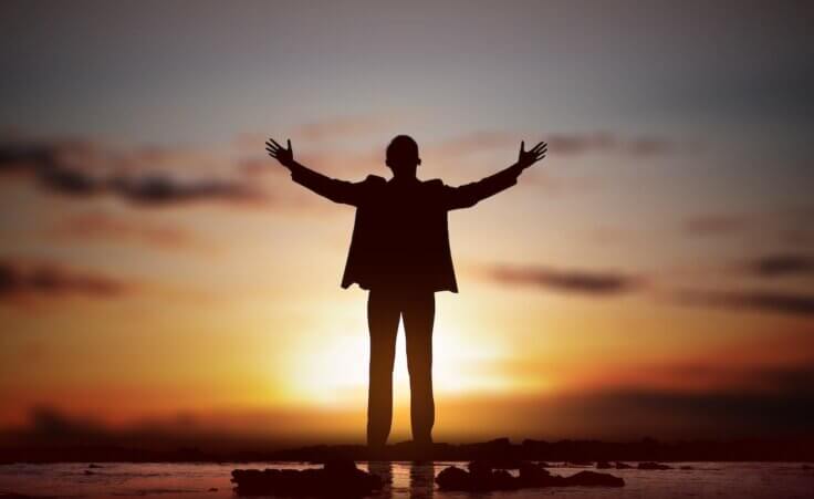 Silhouette of businessman with raised hands, praying to God. By Leo Lintang/stock.adobe.com