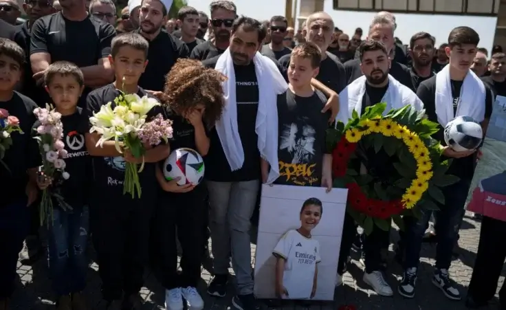 Ibrahim Ibrahim, center, embraces friends of his son, Guevara Ibrahim, 11, who is one of the 12 children and teens, killed in a rocket strike at a soccer field, during his funeral in the village of Majdal Shams, in the Israeli-annexed Golan Heights, Monday, July 29, 2024. (AP Photo/Leo Correa)