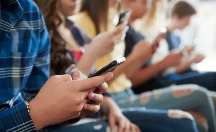 Close up of a line of high school students using mobile phones. By Monkey Business/stock.adobe.com