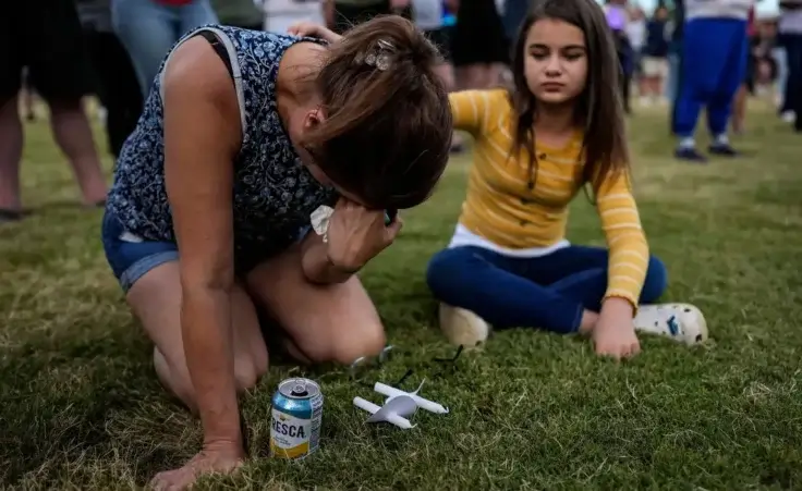 Brandy Rickaba and her daughter Emilie pray during a candlelight vigil for the slain students and teachers at Apalachee High School, Wednesday, Sept. 4, 2024, in Winder, Ga. A shooting at the Georgia high school Wednesday caused at least four deaths and a number of injuries. (AP Photo/Mike Stewart)