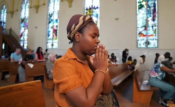 Marie Morette, a congregant of St Raphael Catholic church, prays during Mass in Springfield, Ohio, Sunday, Sept. 15, 2024. (AP Photo/Jessie Wardarski) Haitian immigrant