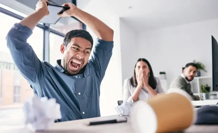 Angry businessman in office about to destroy his equipment out of frustration. By Matthew Cerff/peopleimages.com/