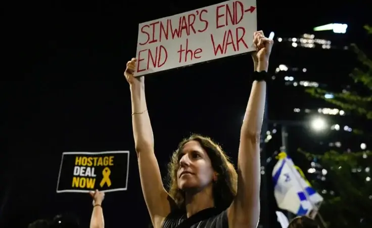 A demonstrator holds a sign about the killing of Hamas leader Yahya Sinwar during a protest calling for a cease-fire deal and the immediate release of hostages held by Hamas on Thursday, Oct. 17, 2024, in Tel Aviv, Israel. (AP Photo/Ariel Schalit)