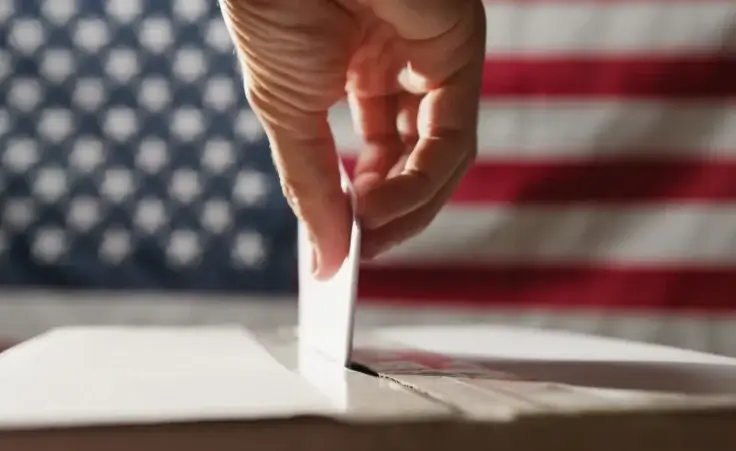 Hand reaching into the ballot box. By francescosgura/stock.adobe.com. Election day 2024