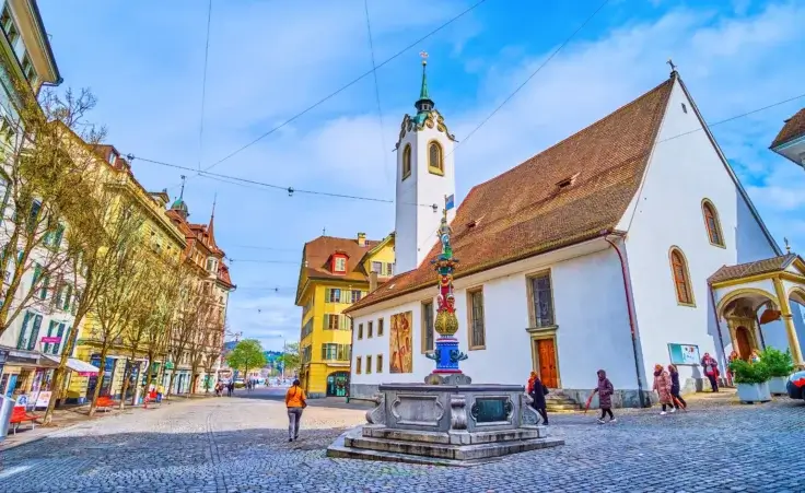 St. Peter's Chapel on Kapellplatz with colorful Fritschi Fountain in Lucerne, Switzerland. By efesenko/stock.adobe.com. AI Jesus avatar