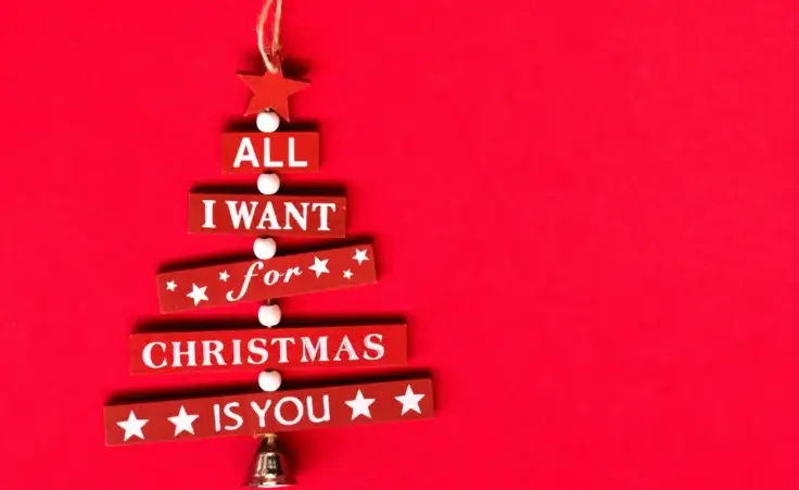 Christmas red tree decoration in red background with sentence, stars, and bell. By Diana/stock.adobe.com Mariah Carey