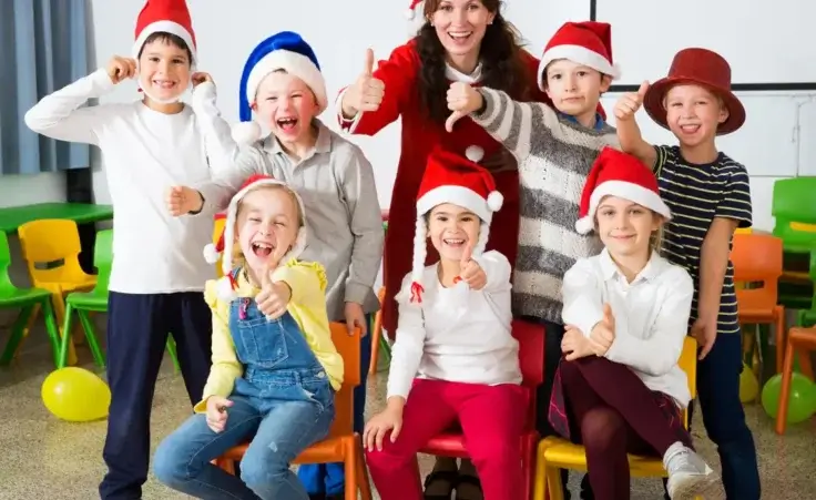 Pupils with teacher in Santa hats giving thumbs up By JackF/stock.adobe.com