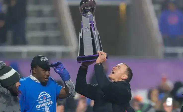 Boise State head coach Spencer Danielson celebrates with safety Seyi Oladipo, the defensive player of the game, with the Championship Trophy after their matchup against UNLV in the Mountain West Championship NCAA college football game Friday, Dec. 6, 2024, in Boise, Idaho. (AP Photo/Steve Conner)