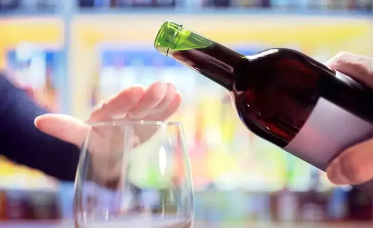 Woman's hand rejecting alcohol from wine bottle in bar to illustrate the Surgeon General's new warning of the link between alcohol and cancer. By Brian Jackson/stock.adobe.com