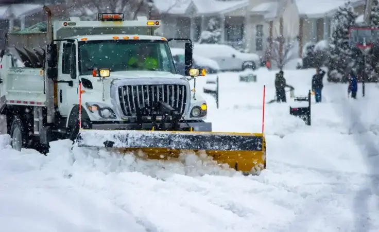 A snowplow truck clearing the roadways of snow after the winter storm covered streets in urban area. By Philip/stock.adobe.com