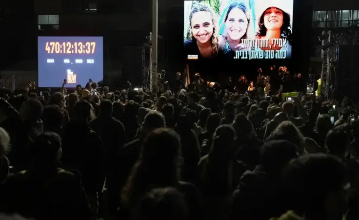 Relatives and friends of people killed and abducted by Hamas and taken into Gaza, react while photographs of the kidnapped women awaiting release Romi Gonen, Doron Steinbrecher and Emily Damari appear on the screen in Tel Aviv, Israel on Sunday, Jan. 19, 2025. (AP Photo/Oded Balilty)