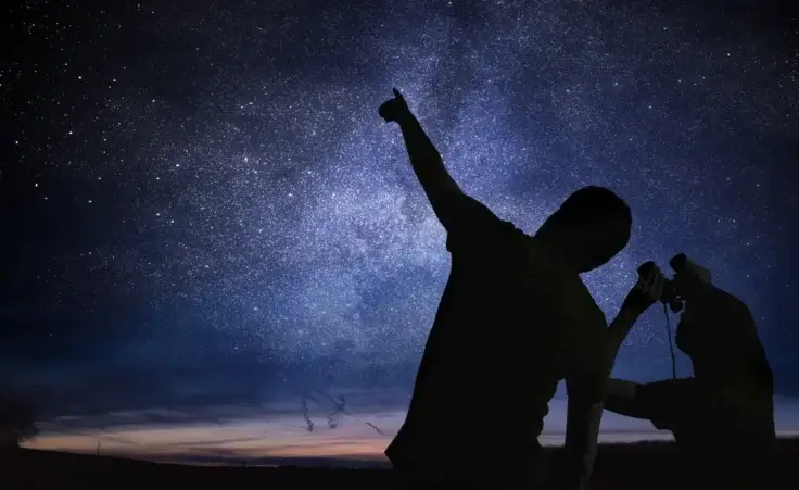 Silhouettes of people observing stars in night sky. Astronomy concept. By vchalup/stock.adobe.com