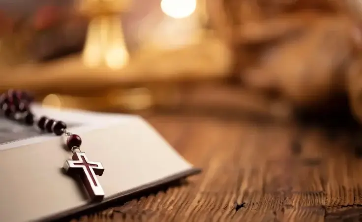 The Cross, monstrance, Holy Bible and golden chalice on wooden altar. By zolnierek/stock.adobe.com