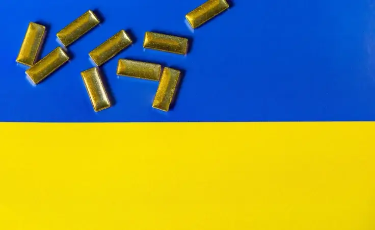 Gold bars scattered across the Ukrainian flag. By MantasŽiličius/stock.adobe.com. United States and Ukraine rare minerals deal